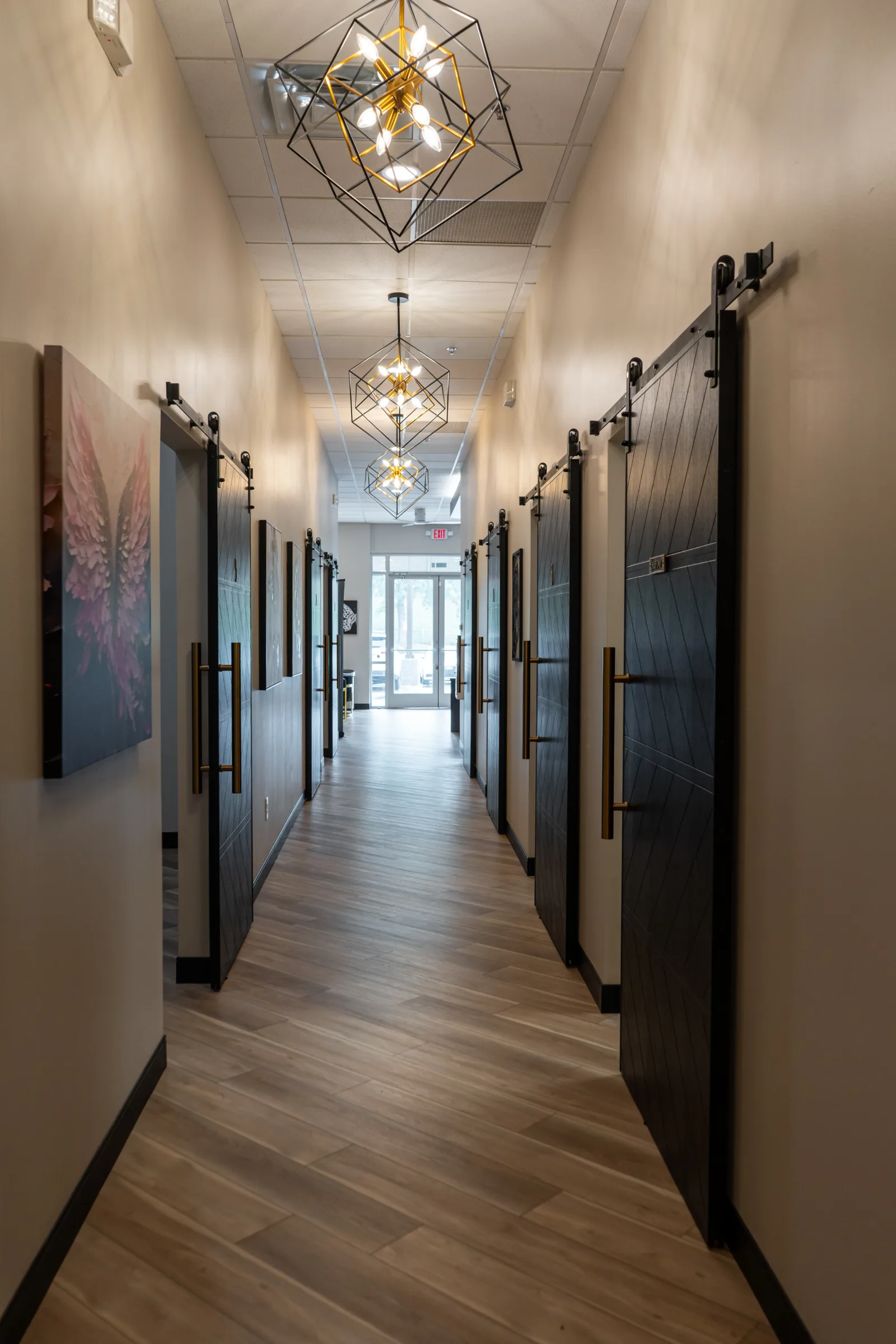 The treatment corridor at Unfiltered Beauty MedSpa, lit by its chandelier