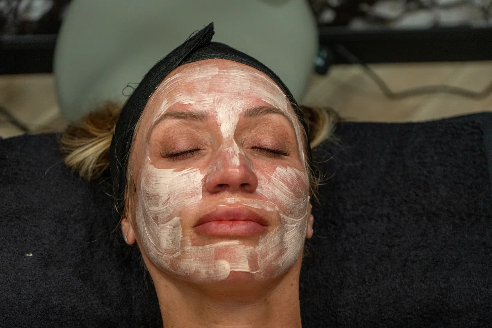 A client lying back under a full clay treatment mask