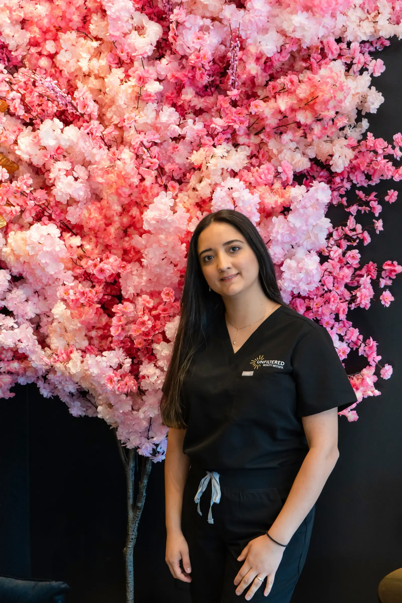A team member standing in front of the pink blossom wall