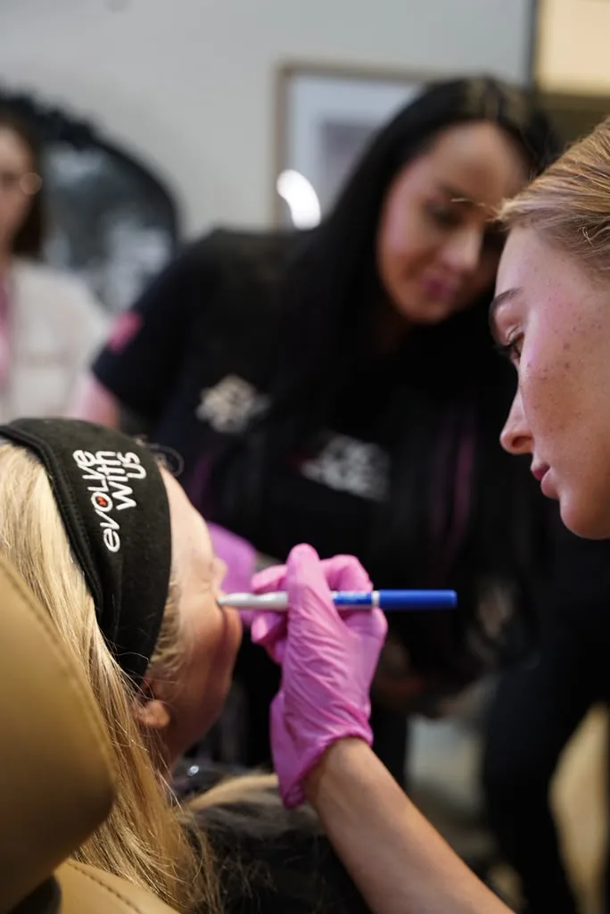 A trainee mapping injection points on a client's forehead with a marker